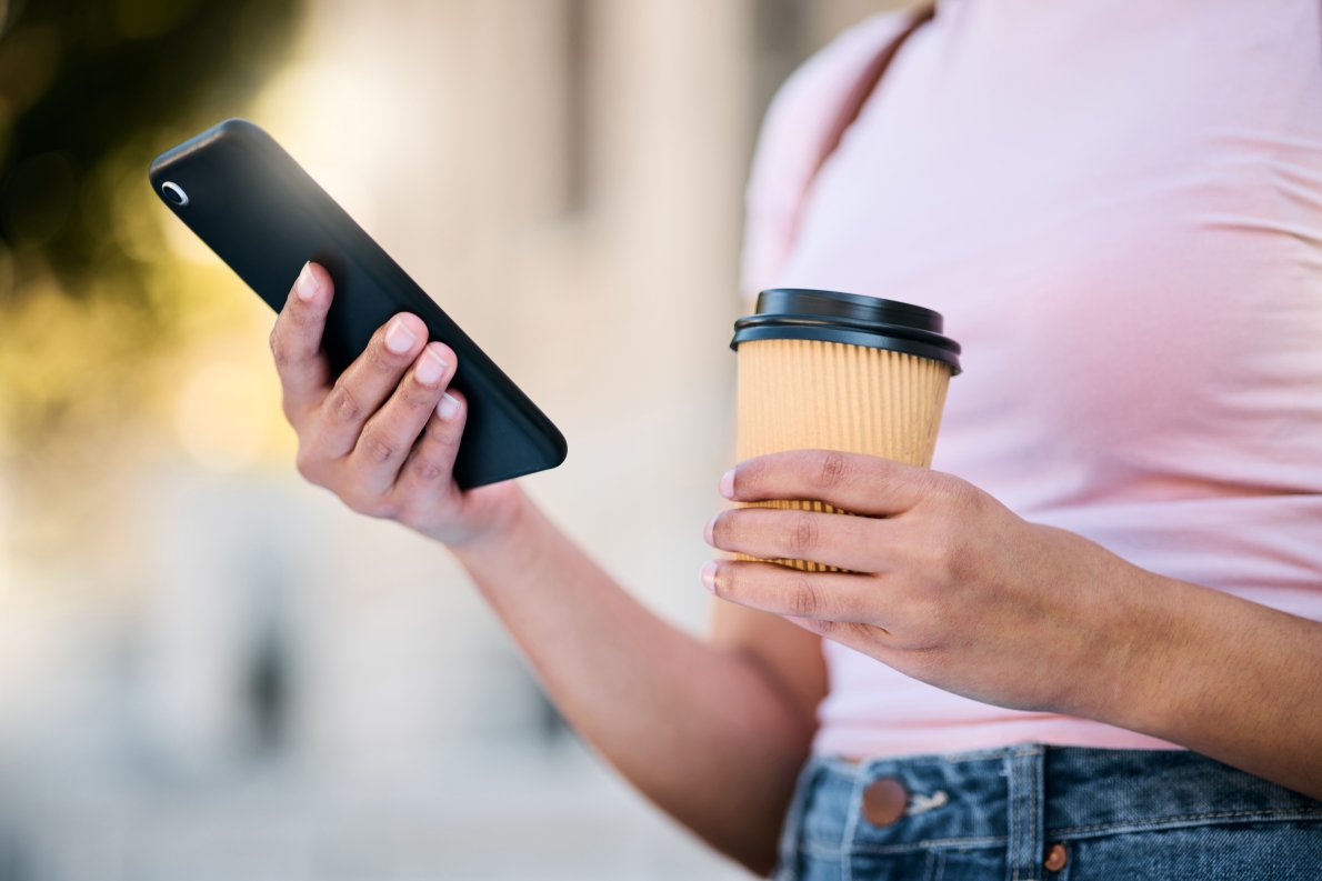 Woman with coffee and phone on hand